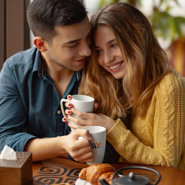 Paar in einem Café beim Date, kuschelt