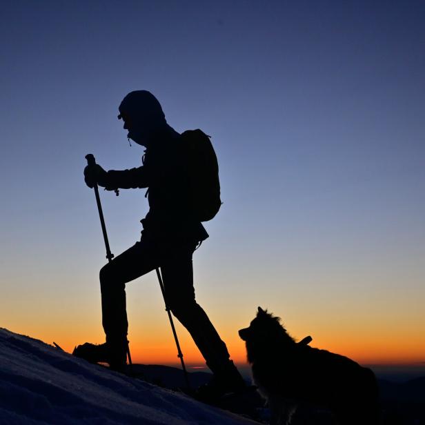 Wanderer mit Hund zu Sonnenaufgang im Almenland