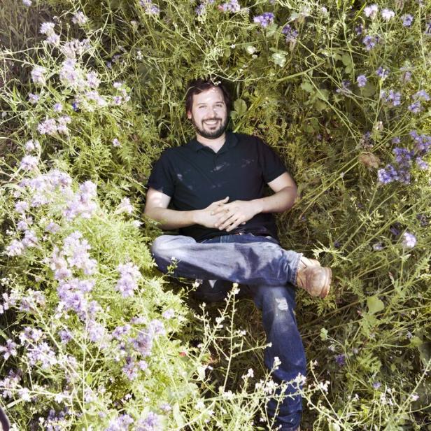 Weinbauer Alwin Jurtschitsch inmitten eines Grünstreifens mit Phacelia-Blüten. Er entwickelt Strategien gegen die Trockenheit