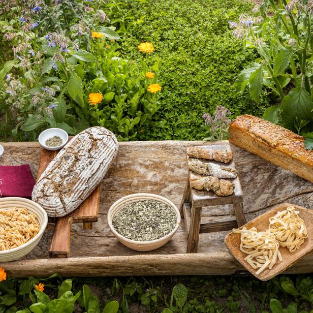 Brot, Gebäck Nudeln und Getreide auf Holzbrettern in einem grünen Garten 