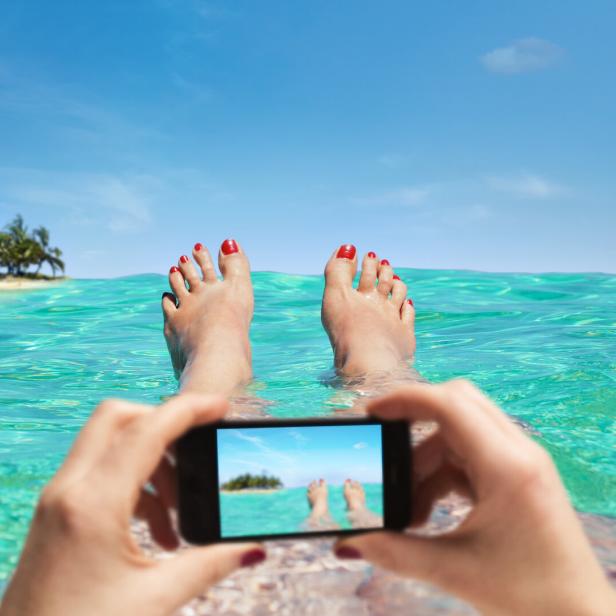 Eine Person liegt am Strand und macht Urlaub vom Meer.