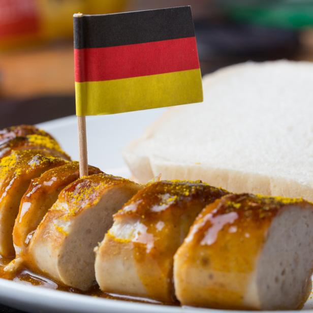 Auf einer Currywurst steckt eine Papierflagge mit den deutschen Farben Schwarz, Rot, Gold