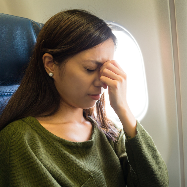 Frau sitzt ängstlich im Flugzeug, was man bei Flugangst machen sollte 