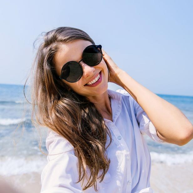 Junge Frau mit Sonnenbrille macht ein Selfie von sich