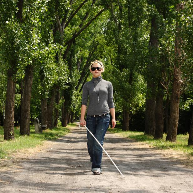 Frau mit Blindenstock im Park