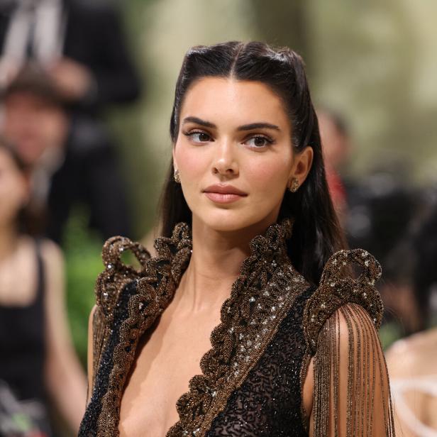 Kendall Jenner trägt ein aufwendiges, dunkles Kleid mit goldenen Verzierungen.