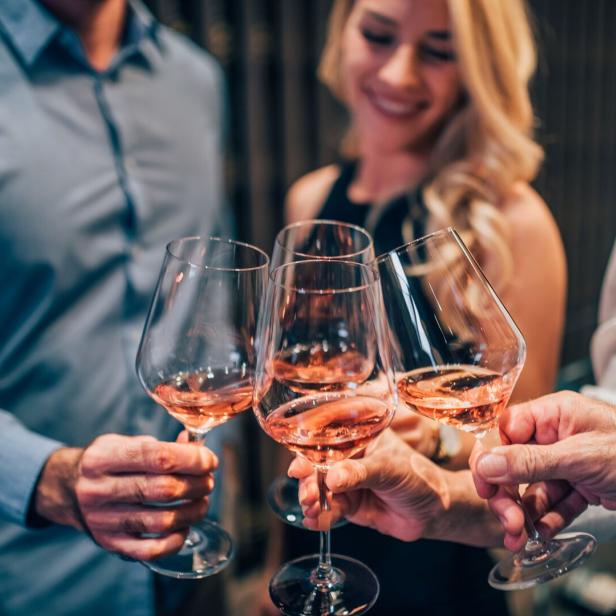 Vier Personen stoßen mit Rosé-Schaumwein an