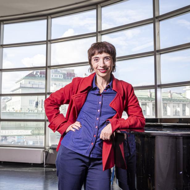 Ruth Brauer-Kvam steht an einem Klavier auf der Probenbühne der Wiener Volksoper. Der Raum hat ein großes Fenster. Im Hintergrund ist die Stadtbahn-Station Währiger Straße.