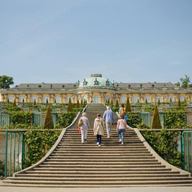 Besucher steigen die Treppe zum Schloss Sanssouci in Potsdam hinauf.