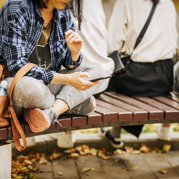 Eine Frau sitzt mit ihrem Smartphone auf einer Bank