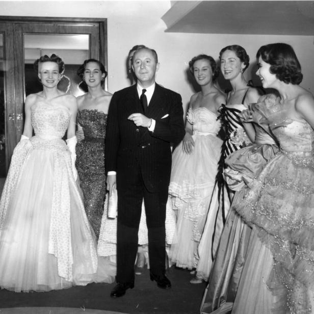 Christian Dior mit sechs Models in seinen eleganten Abendroben im Jahr 1950