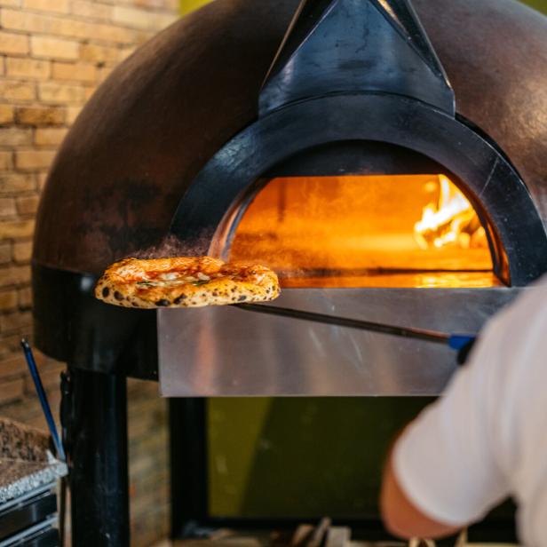 Mann schiebt Pizza in den Ofen