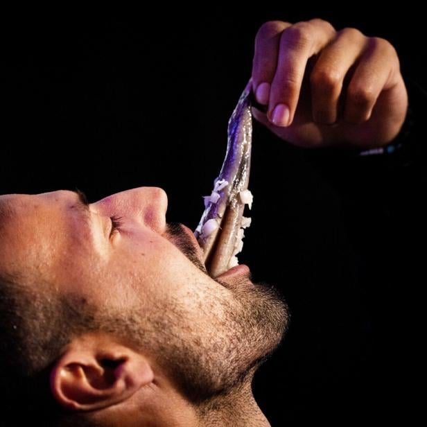 Ein Mann isst einen Hering mit Zwiebeln auf traditionelle Weise.