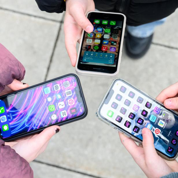 Drei Personen halten ihre Smartphones mit verschiedenen App-Anordnungen in die Kamera.