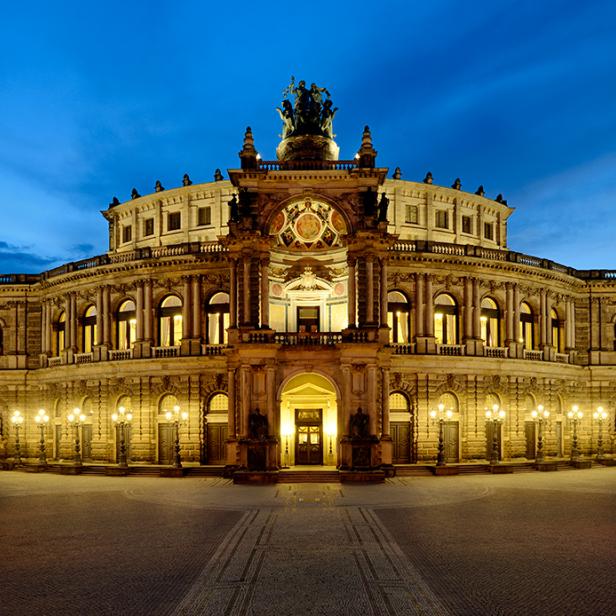 Die Semperoper in Dresden bei Nacht, beleuchtet mit warmem Licht.