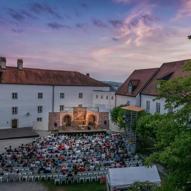 Eine Freilichtaufführung mit Publikum vor einer historischen Gebäudekulisse.
