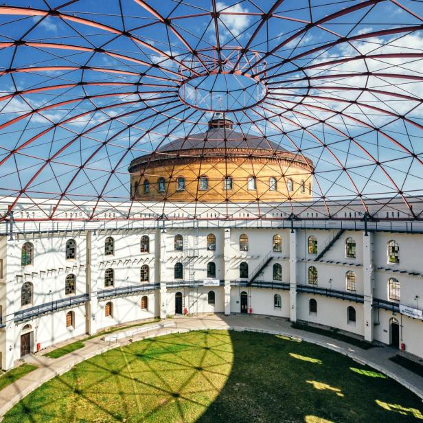Innenansicht des EUREF-Campus in Berlin mit roter Stahlkuppel und begrüntem Innenhof.
