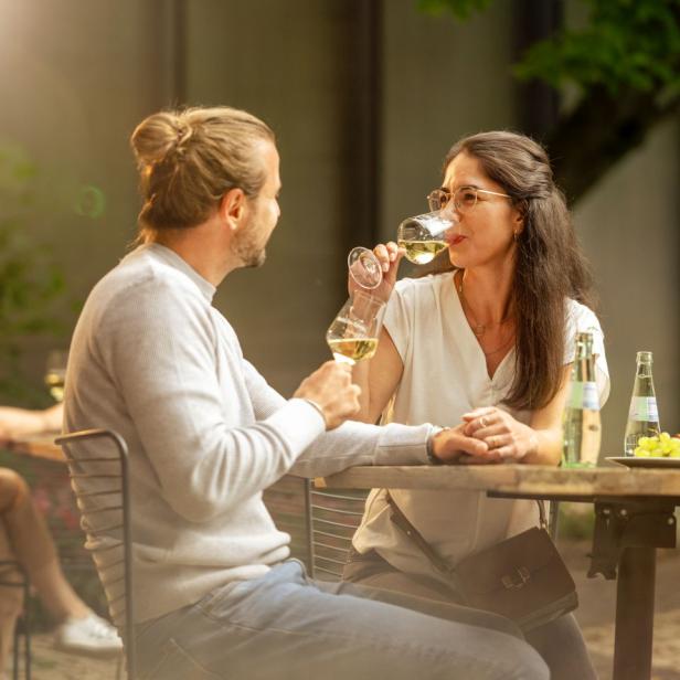 Ein Paar sitzt im Freien und genießt ein Glas Weißwein.