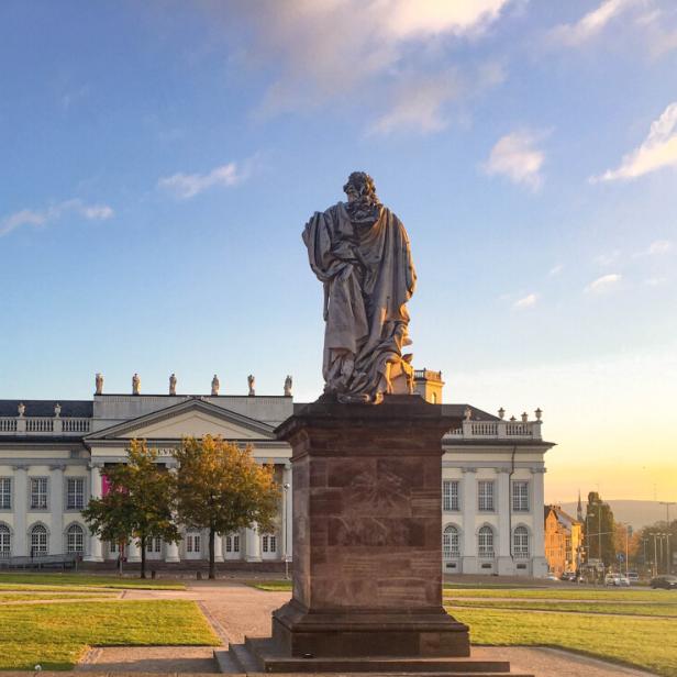 Fridericianum und Statue von Friedrich II., Kassel, Hessen, Deutschland Statue eines Mannes vor einem Gebäude, das die architektonische Schönheit der Umgebung betont.