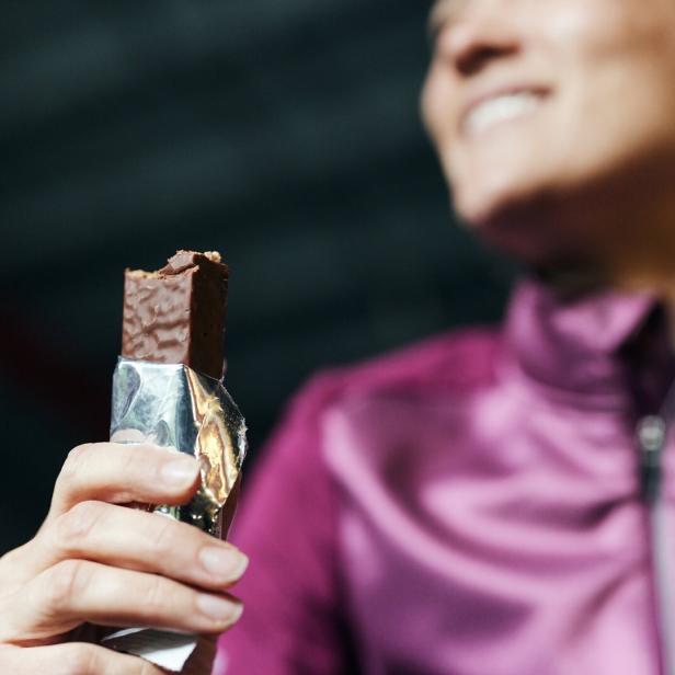 Eine Frau isst einen Proteinriegel.