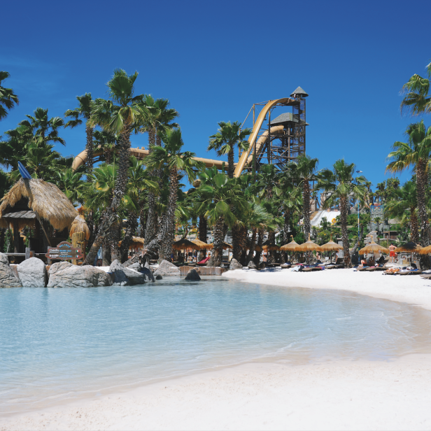 Auf dem Bild ist ein Wasserpark in Jesolo zu sehen. Klares, türkises Wasser und Rutschen im Hintergrund.