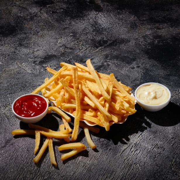 French fries in fryer basket on dark background