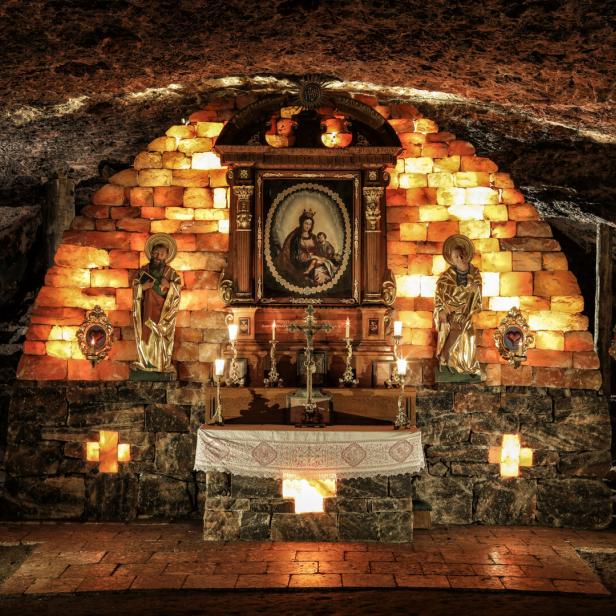 Eine Kapelle in einer Höhle, geschmückt mit Heiligenstatuen und einem Marienbild.