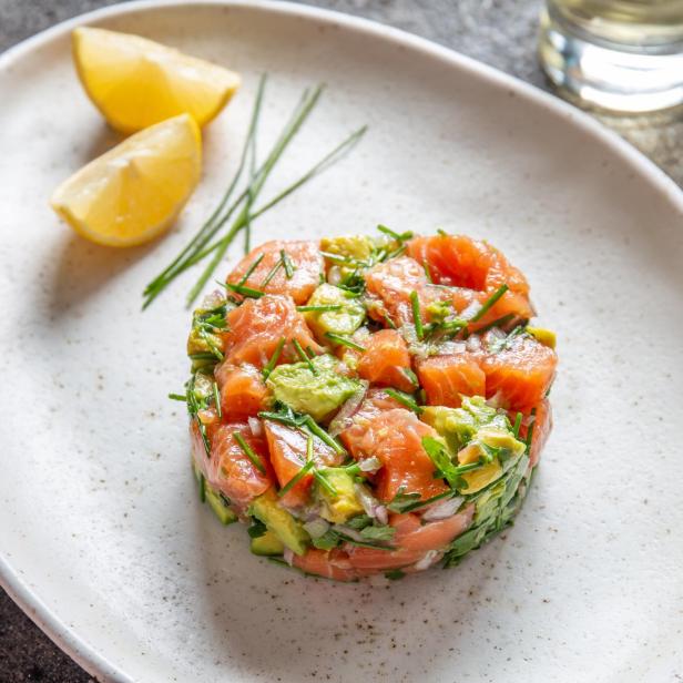 PERUVIAN FOOD. Salmon ceviche with avocado, spring onion and lemon on white plate served with white wine PERUVIAN FOOD. Salmon ceviche with avocado, spring onion and lemon on white plate served with white wine
