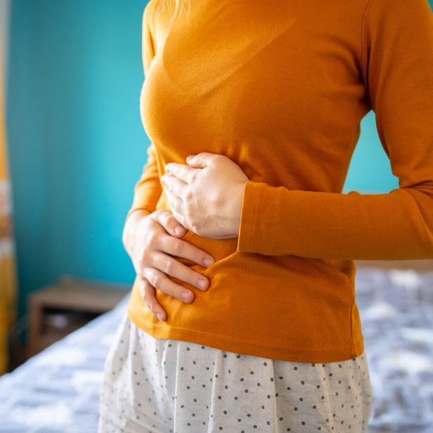 Frau hält sich den schmerzenden Bauch.