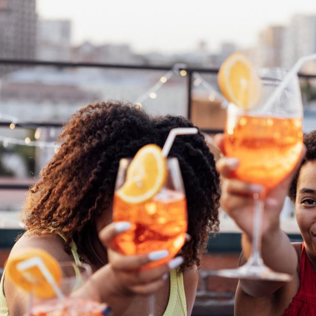 Freunde - offenbar in einer Rooftop-Bar in New Yorkt - prosten einander mit Aperol Spritz zu