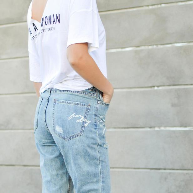 Eine Frau trägt Jeans und ein weißes T-Shirt.