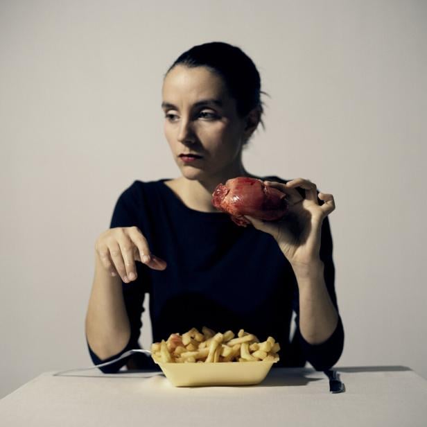 Die Künstlerin hinter einer großen Schale Pommes Frites - dazu hält sie ein (wohl künstliches) Herz in der Hand