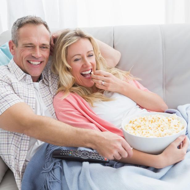 Couple eating popcorn while watching television