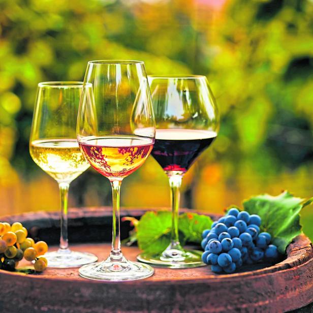 Three glasses of white, ros?É¬© and red wine and an old wooden barrel, with winery still life