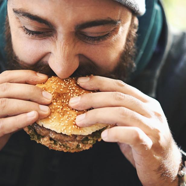 Mann beißt in Burger.