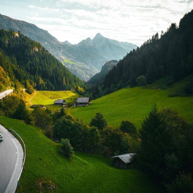 Ein Auto fährt eine kurvenreiche Straße in den Bergen entlang.