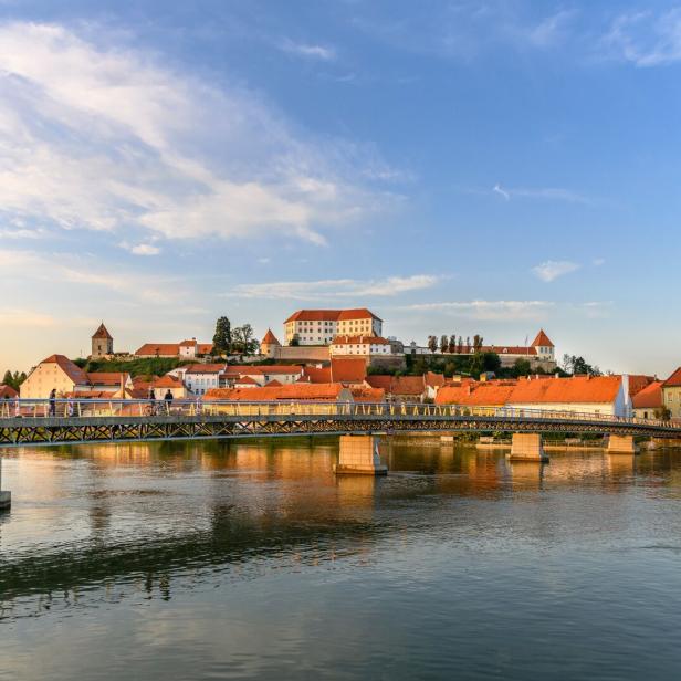 Ptuj: Fußgängerbrücke über die Drau, hinten die mittelalterliche Schlossanlage am Burghügel über der Stadt.