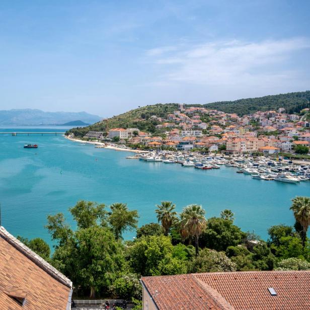 Aussicht vom Hügel auf die Bucht von Trogir, Kroatien, mit sanften Hügeln und klarem Wasser im Hintergrund.