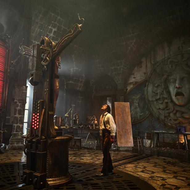 Filmszene: Victor Frankenstein steht in seinem Labor und sieht auf seine Kreatur, die auf einem Kreuz aufgepannt ist.