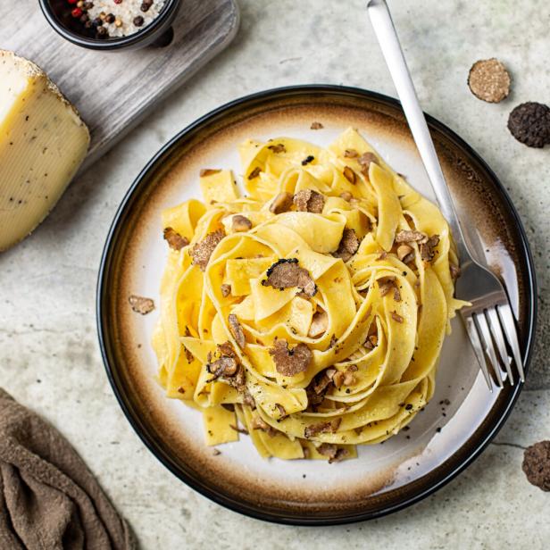 Top view of truffle fettuccine with mushrooms, long egg pasta. Italian first course made with hard cheese and butter. Ingredients.