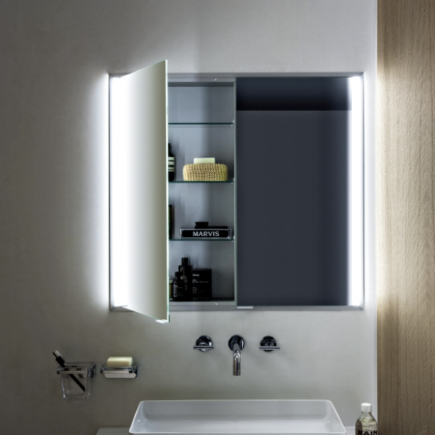 Moderner Badezimmerspiegel mit geöffneter beleuchteter Tür, weißes Waschbecken, Seifenspender und graue Wand.