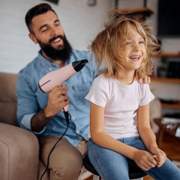 Father drying his cute little daughter's hair with blowdryer