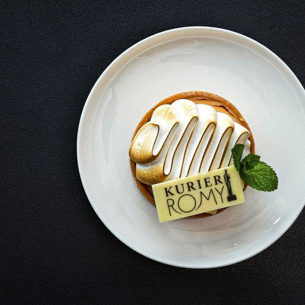 Ein kleines Küchlein mit einem Kurier-Romy-Schokoblättchen und einem Minzblatt.
