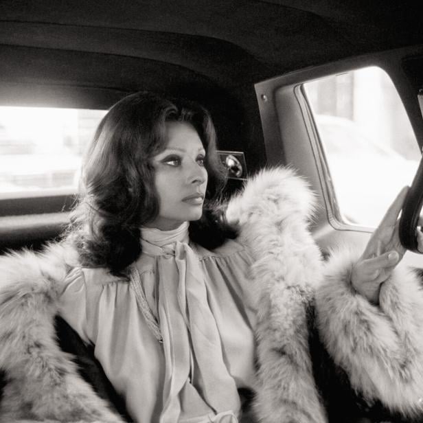 Sophia Loren im Auto, sie hat einen Pelzmantel an und sieht zum Fenster hinaus