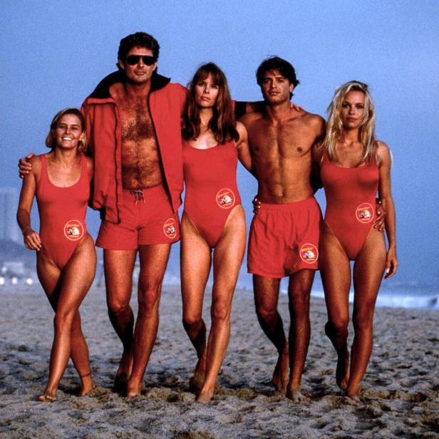 Die Rettungschwimmer aus den Neunzigern am Strand - sie haben sich ihre Arme um die Schultern gelegt.