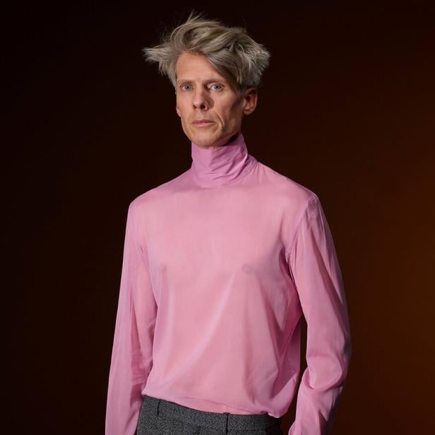 Ein blonder Mann in einem rosa Pulli