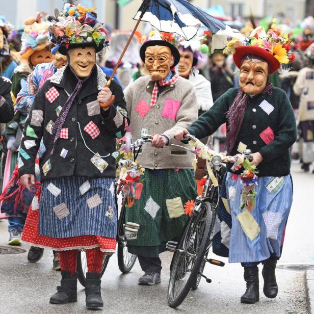 Eine Gruppe verkleideter Menschen mit Masken und bunten Kostümen zieht durch die Straße.