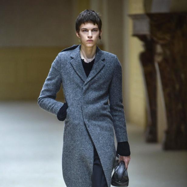 Ein sehr dünner Mann im Mantel bei der Prada Show