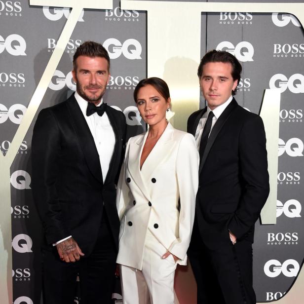 David Beckham, Victoria Beckham und ihr Sohn Brooklyn posieren gemeinsam im eleganten Outfit auf dem roten Teppich bei einer GQ-Veranstaltung.
