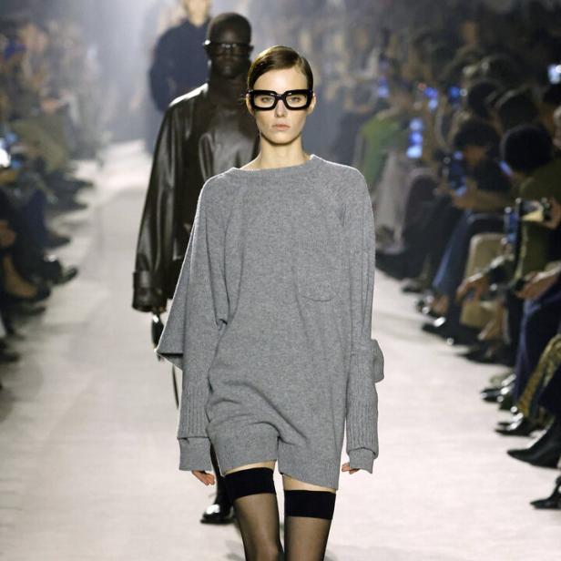 Model im langen grauen Pulli mit halterlosen Strümpfen auf dem Laufsteg